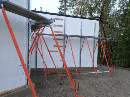 Orange alignment bracing and turnbuckle feet supporting an ICF wall on site ahead of the pour